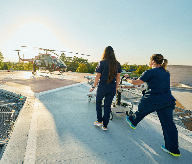 Two nurses pushing gurney towards helicopter on rooftop