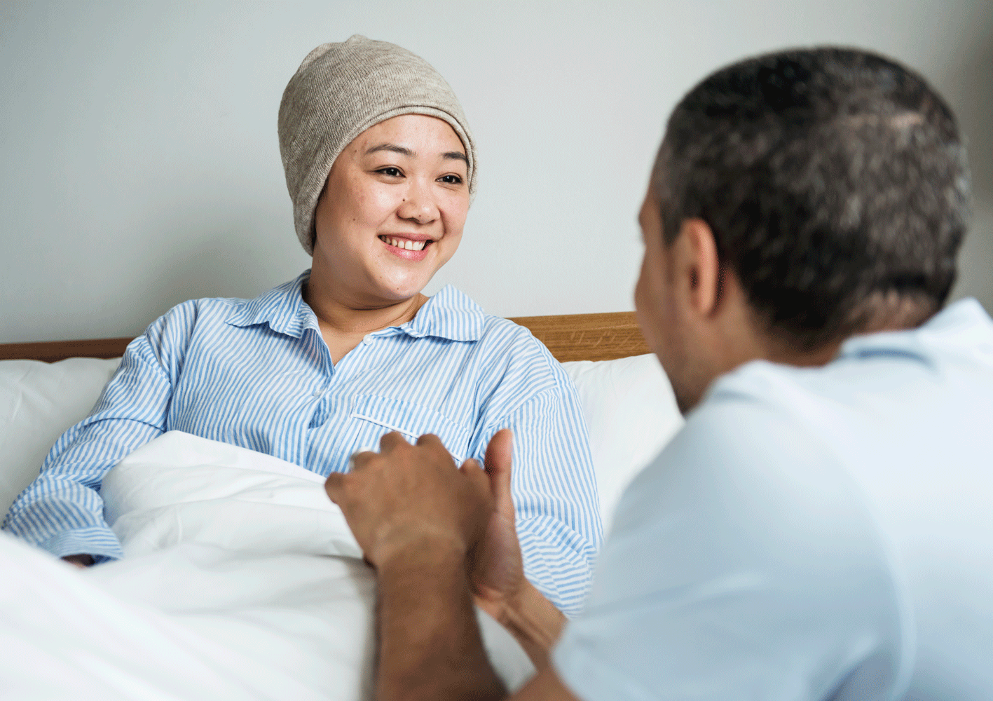 Woman in hospital bed holding partner's hand