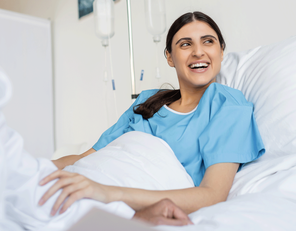 Young woman in hospital bed smiling