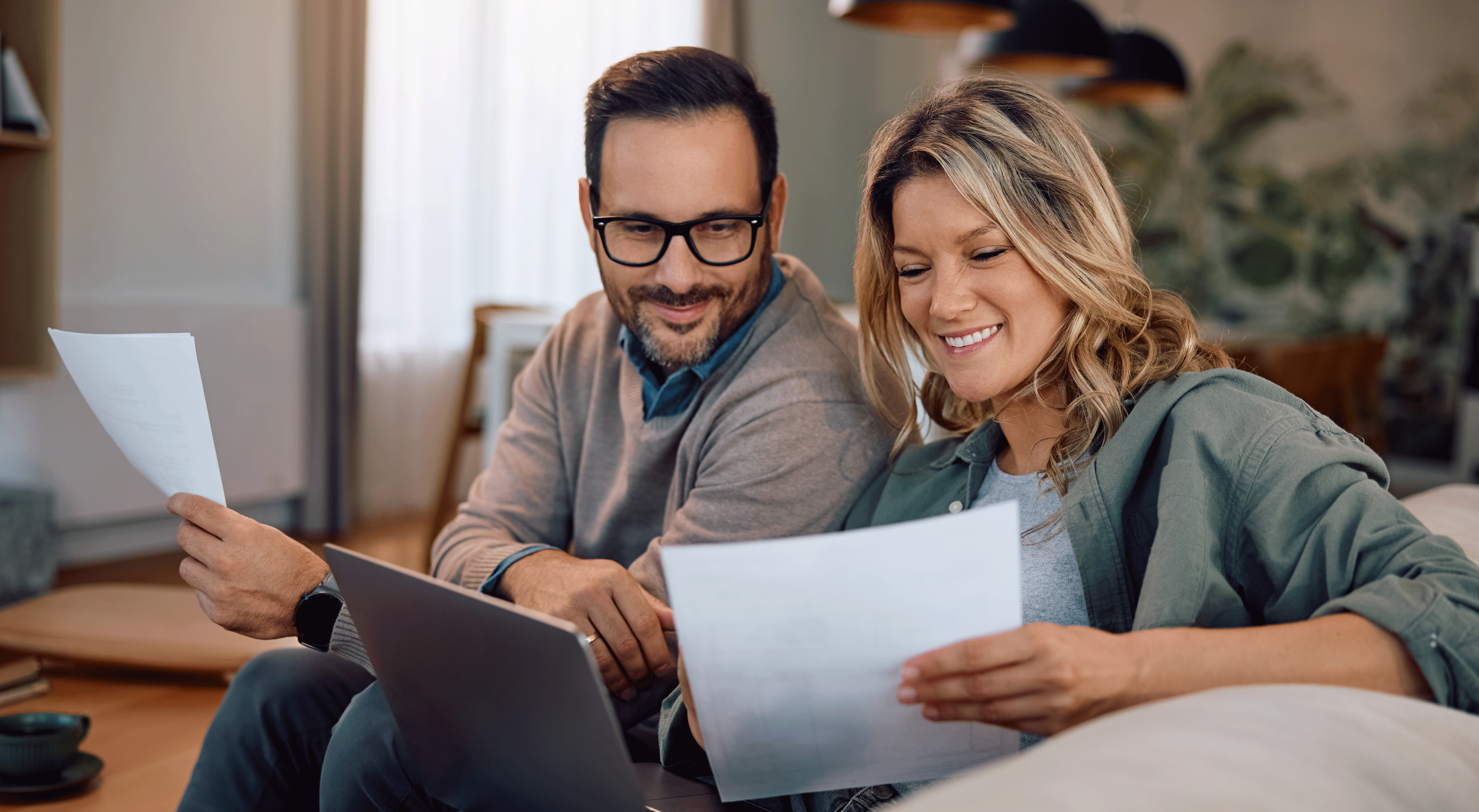 Couple smiling while looking at document at home