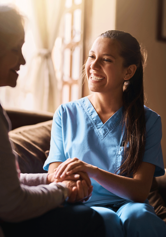 Nurse smiling holding elderly woman's hand