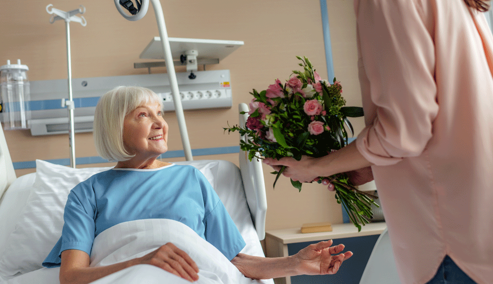 Woman receiving flowers from daughter in hospital bed