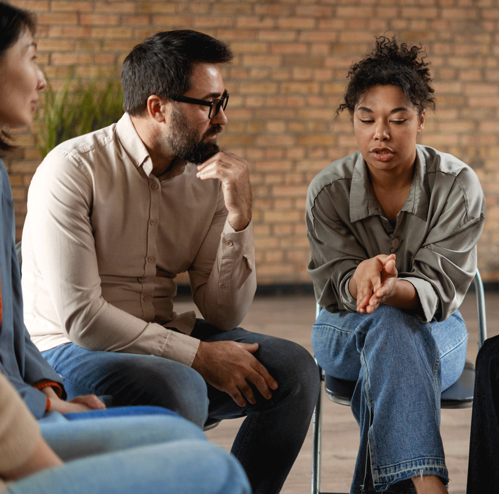 Diverse adults sitting and talking in group therapy session