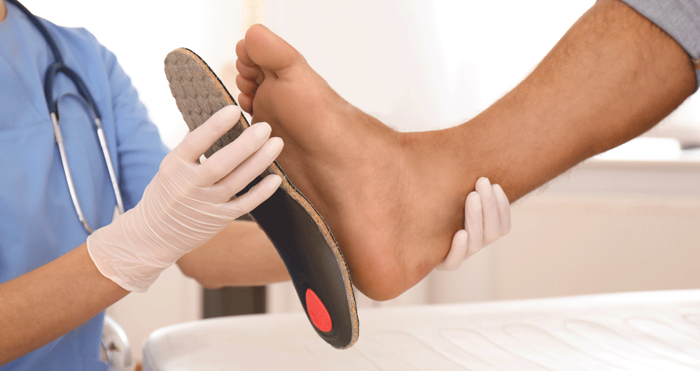 Hands holding insole to patient's foot Hands holding insole to patient's foot