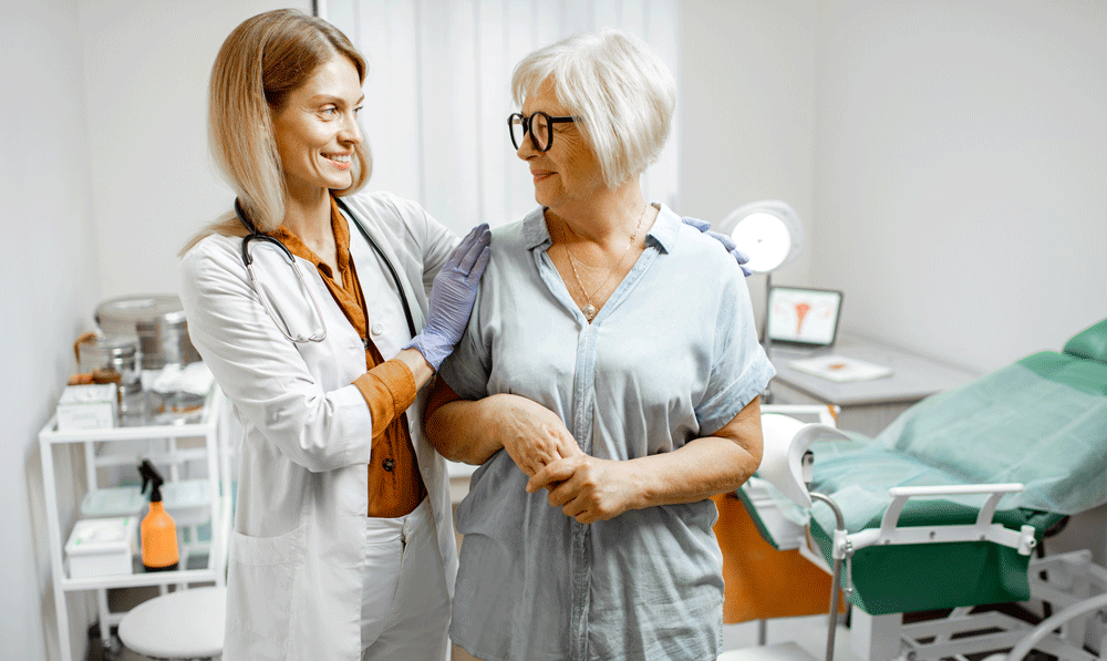 Gynecologist talking to senior woman in exam room