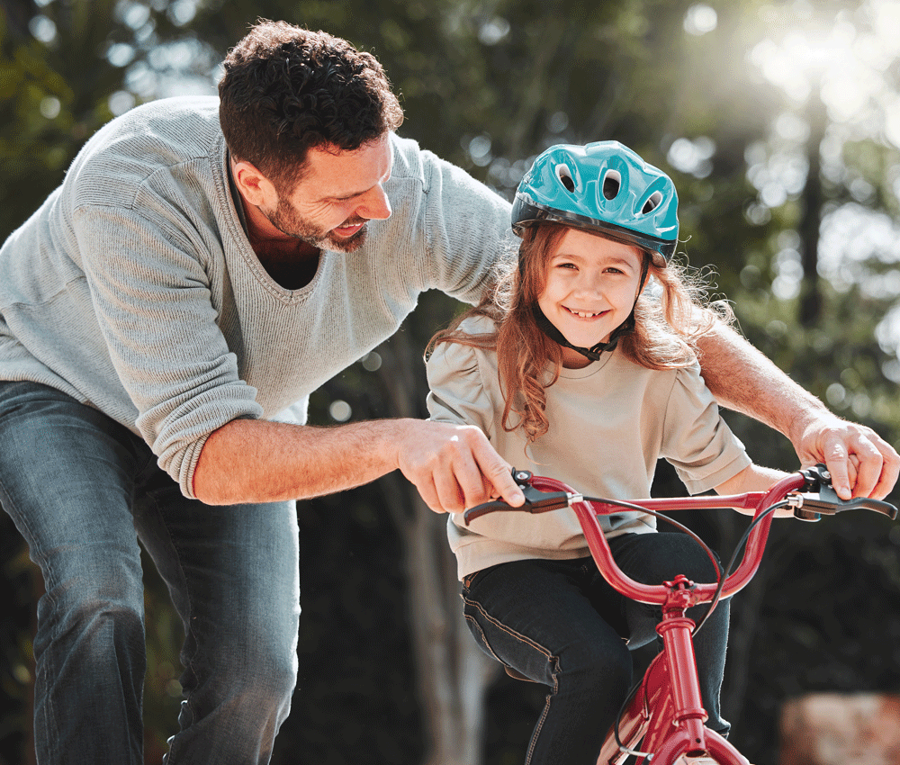 Father teaching daughter how to ride bike