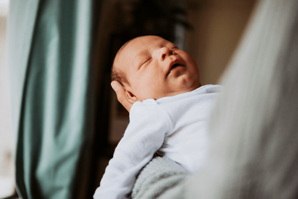 Infant sleeping in arms of adult