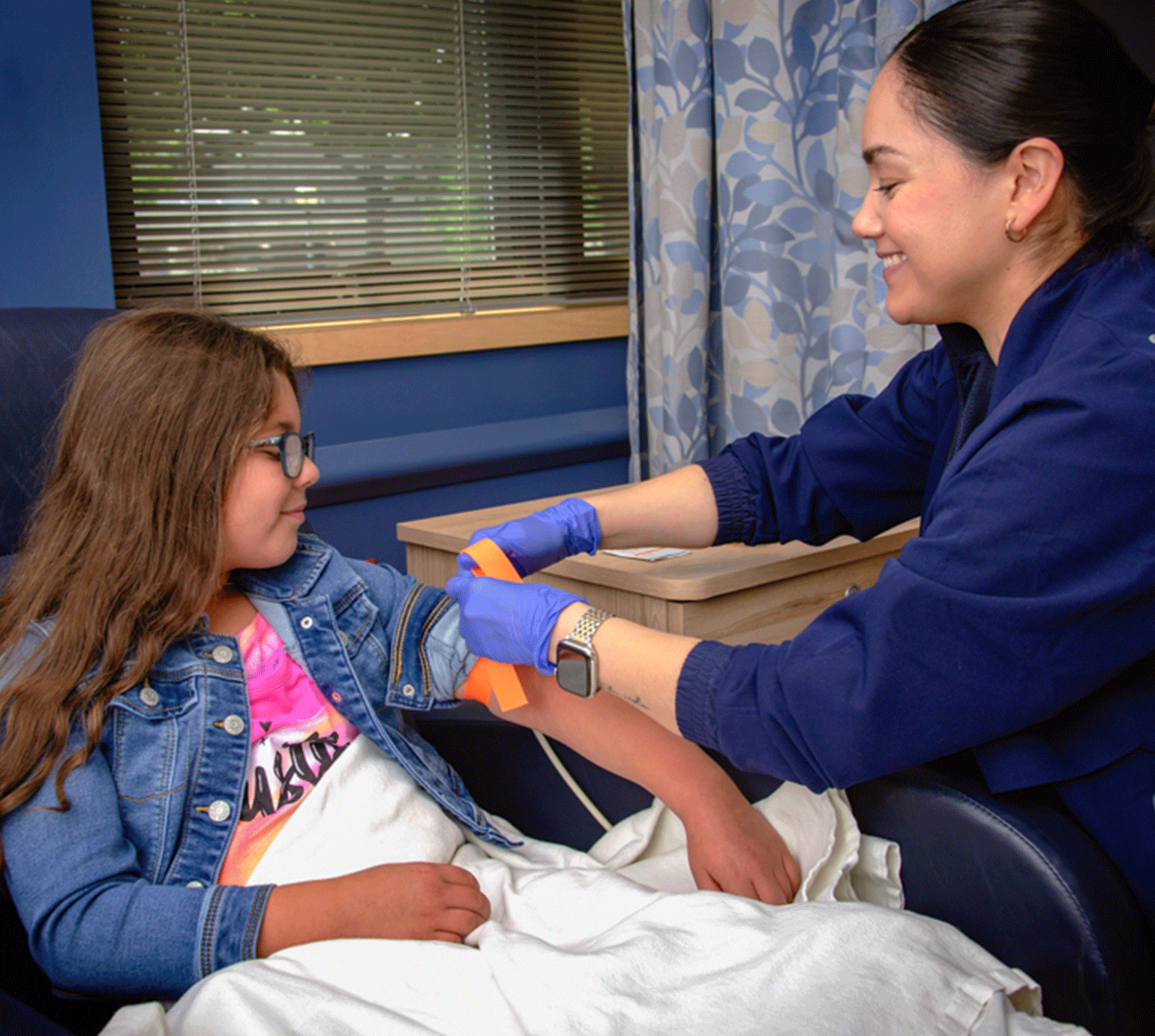 Female MHS nurse prepping young girl for infusion service