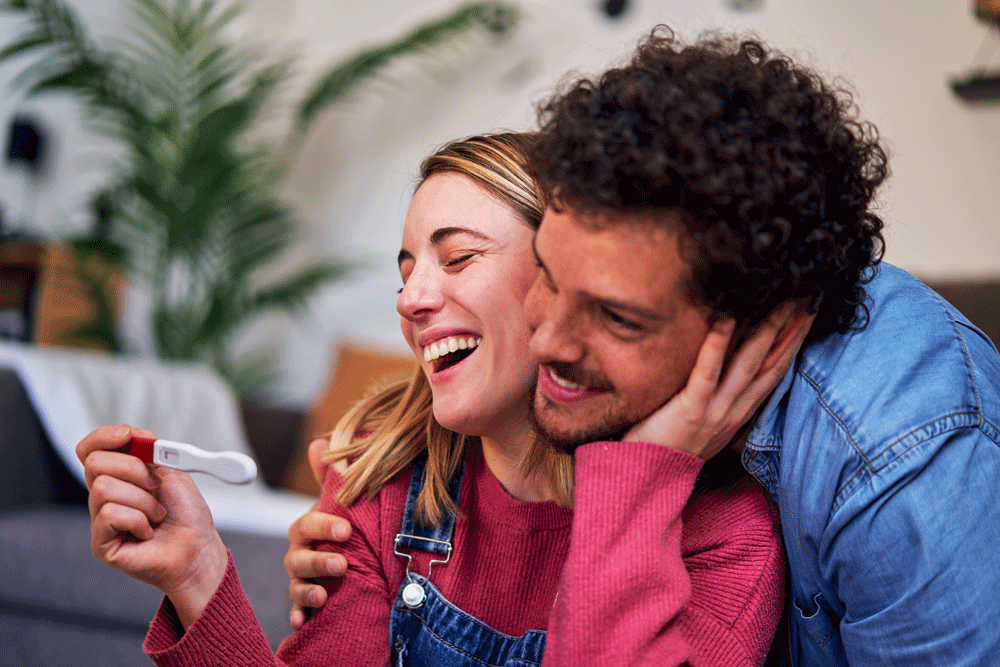 Couple celebrating positive pregnancy test at home Couple celebrating positive pregnancy test at home