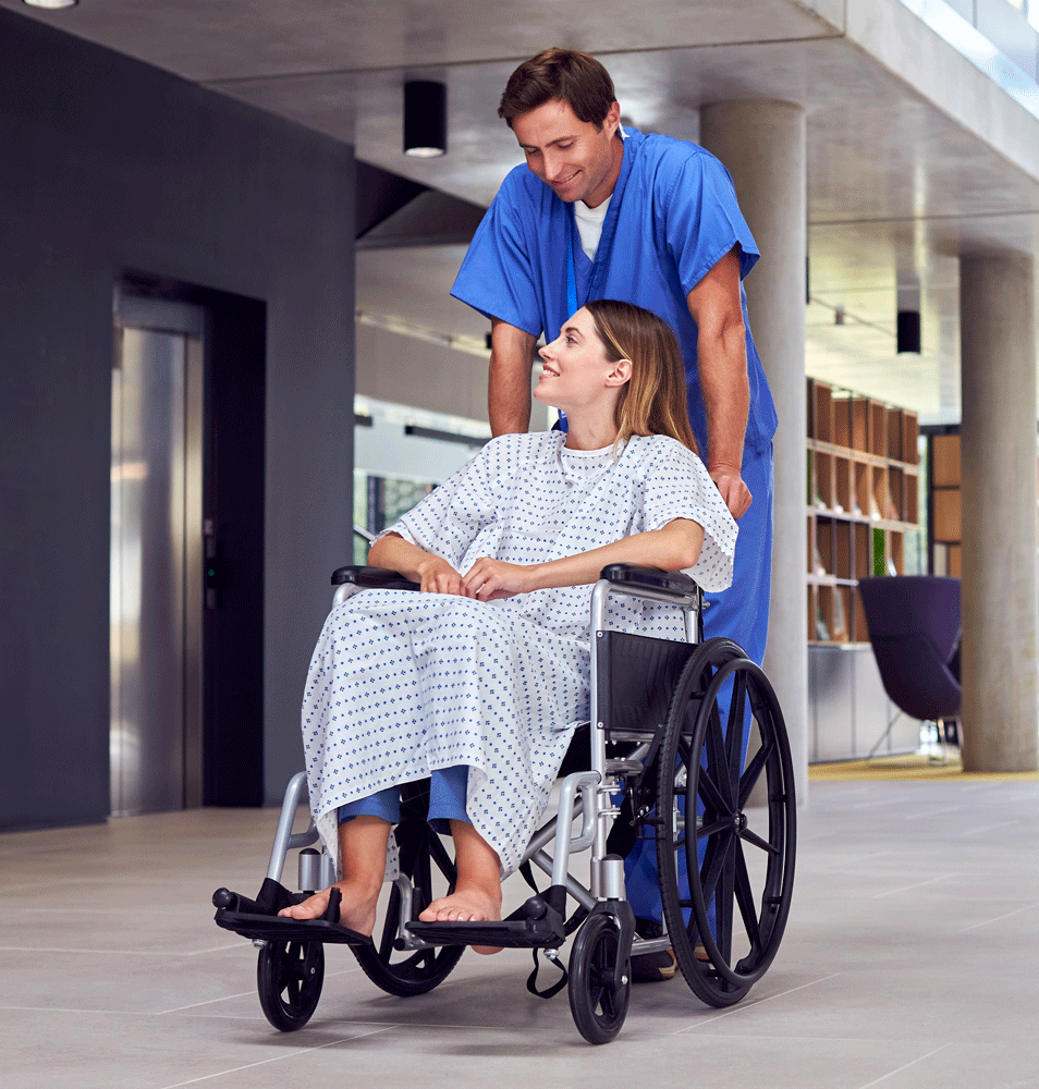Nurse pushing patient in wheelchair through hospital