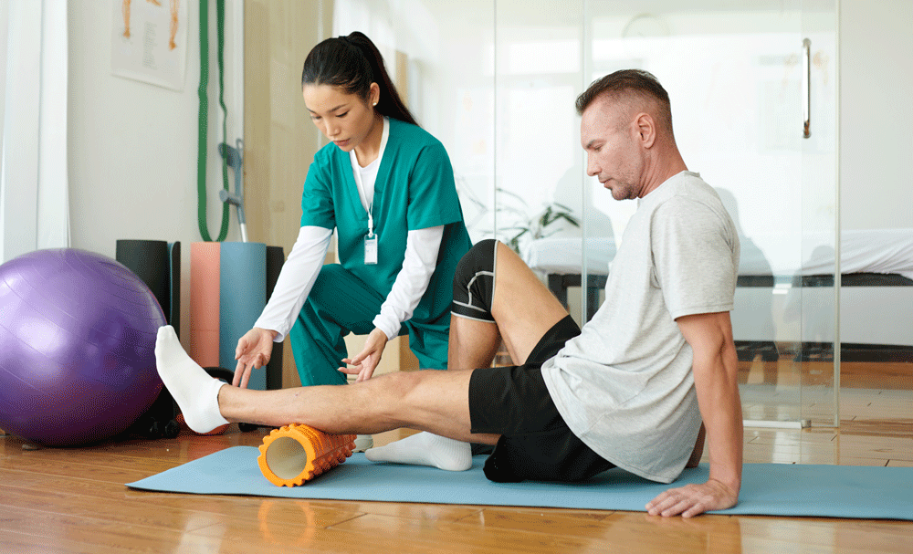 Nurse helping male patient with physical therapy exercise on leg