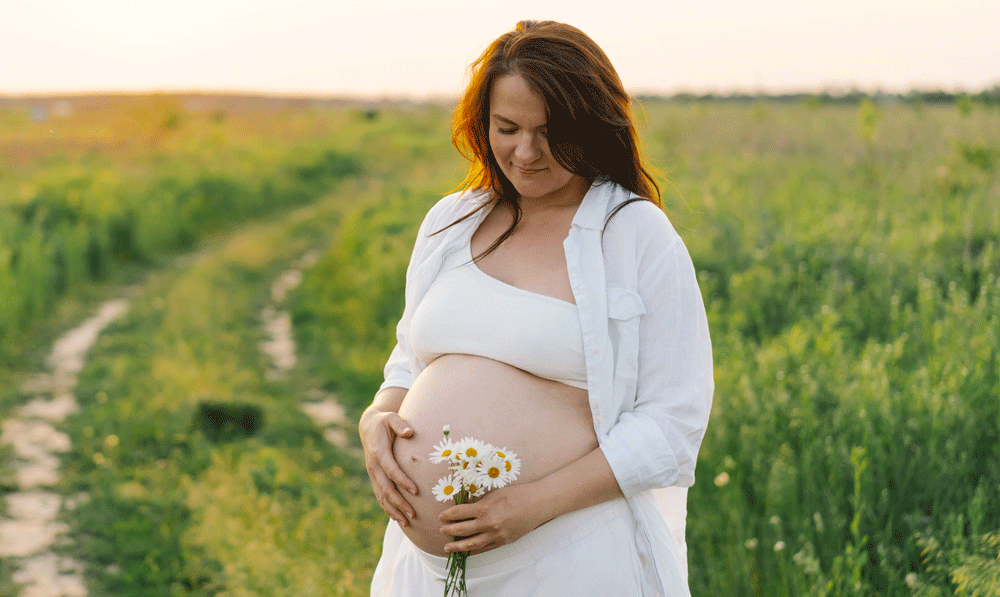 Pregnant woman in field at sunset