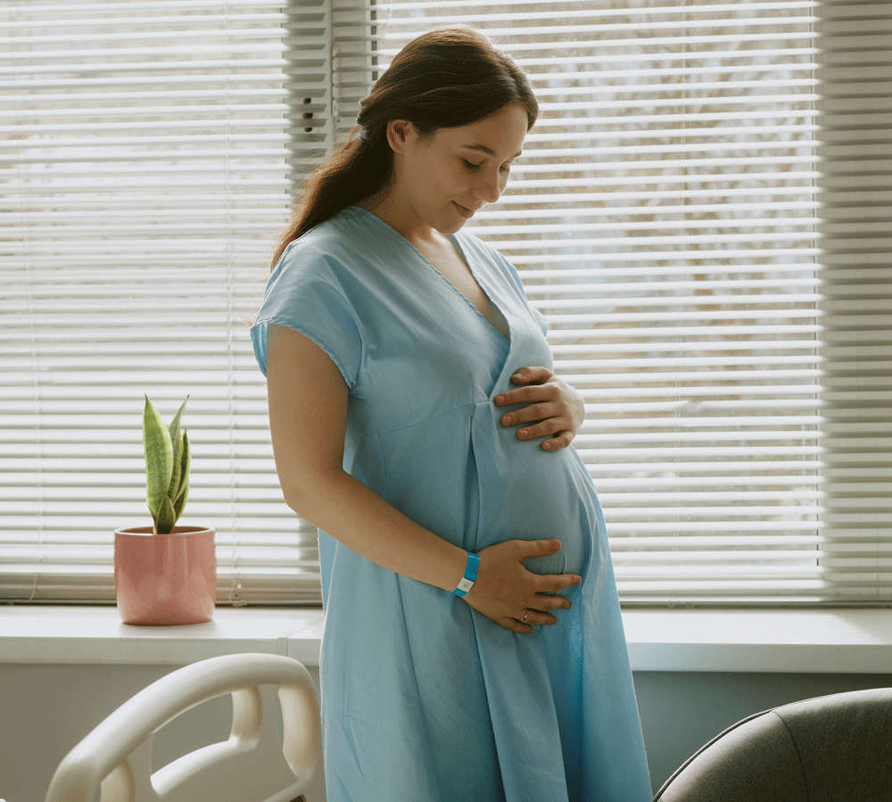 Pregnant woman in hospital holding and smiling at belly Pregnant woman in hospital holding and smiling at belly