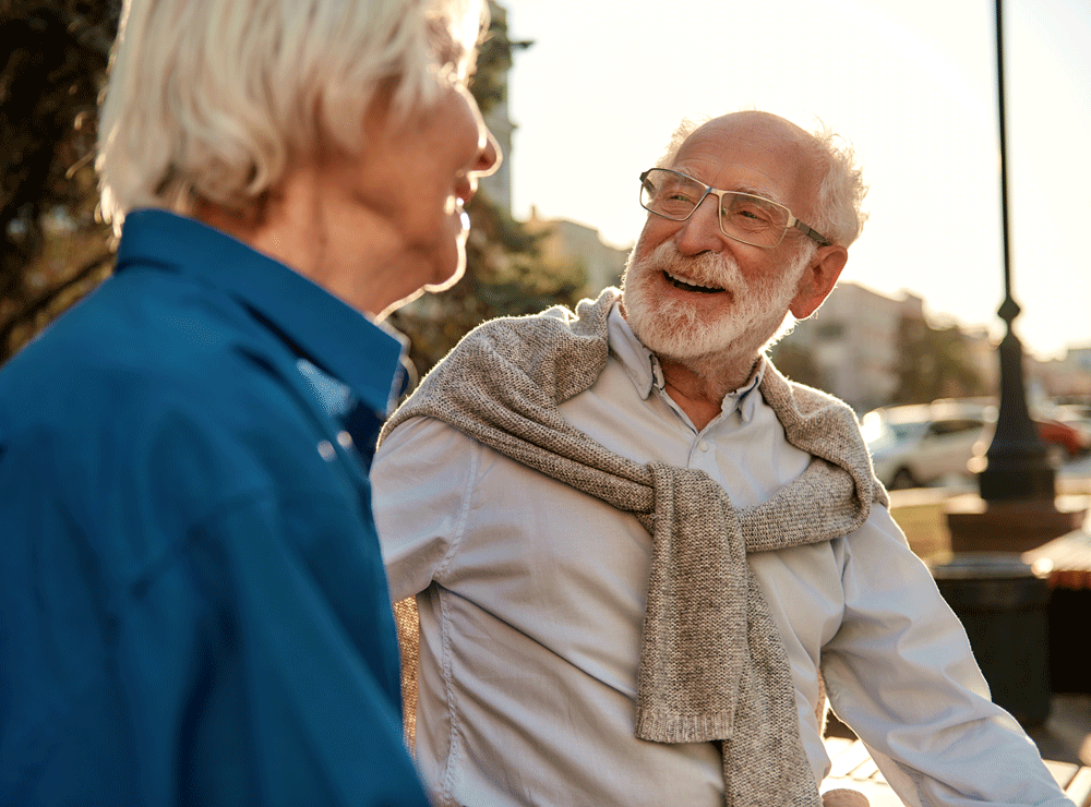 Senior man smiling while talking with woman in park