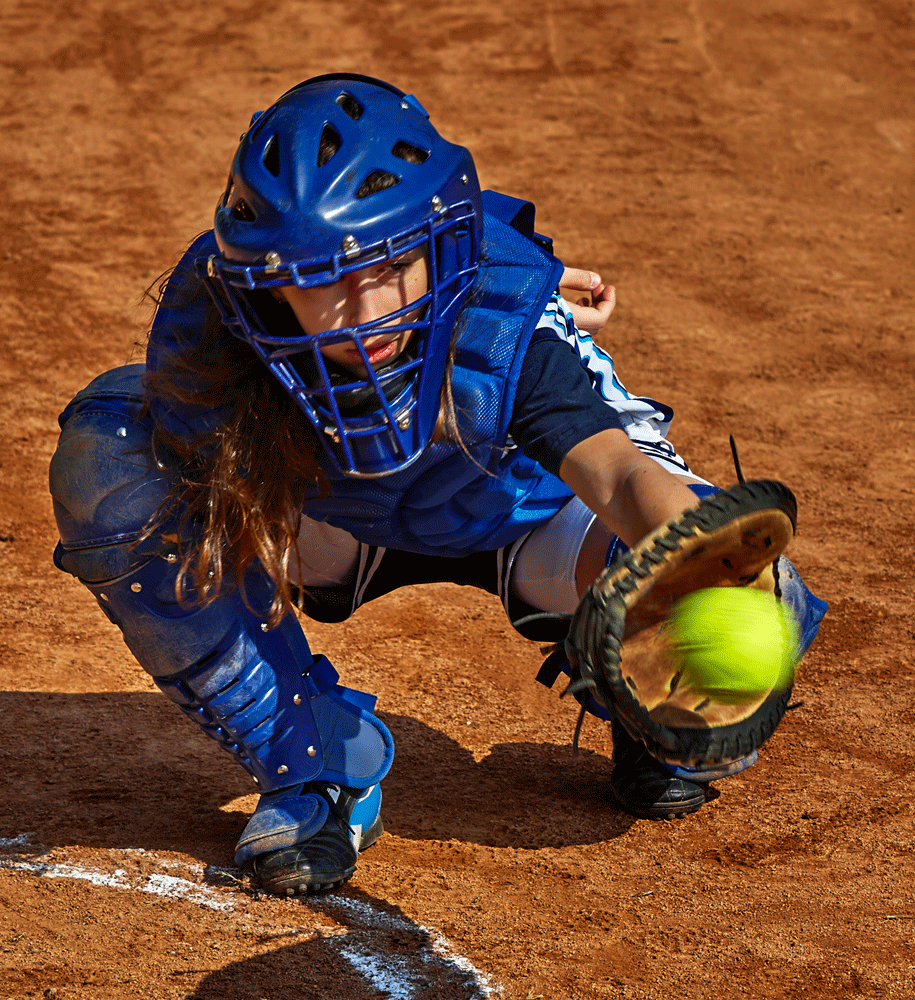 Teen girl catching softball in catcher's gear